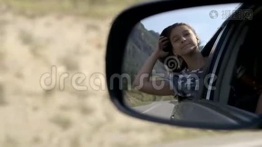 女孩坐在一辆移动的汽车里放松，坐在靠窗的山上。 在车里的倒影视频