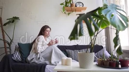 斯堪的纳维亚的生活方式-年轻漂亮的女人躺在沙发上，喝咖啡，享受生活视频