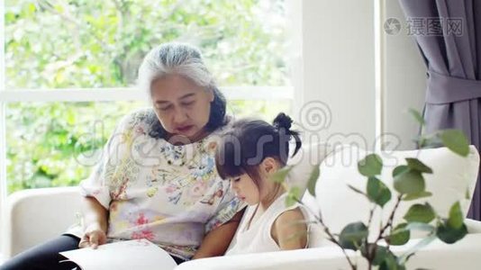 老奶奶和小孙女在沙发上看书视频