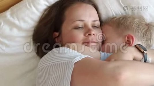 早上妈妈和小儿子在床上的肖像，他们醒来拥抱。视频