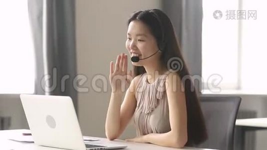 戴着无线耳机视频通话笔记本电脑的亚洲女商人微笑视频