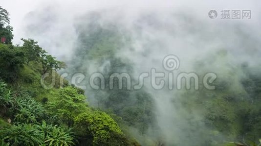 云层和雾气覆盖两山之间山谷的热带丛林森林的4k镜头视频