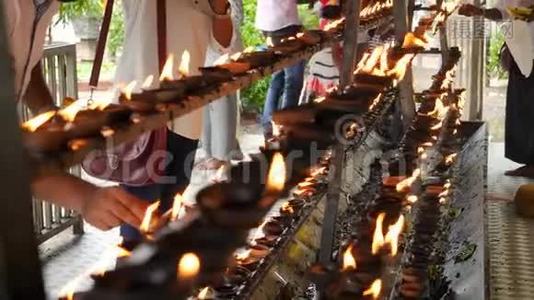 4k佛教崇拜者的视频，在佛寺祭坛上点燃并点燃燃烧的油灯视频