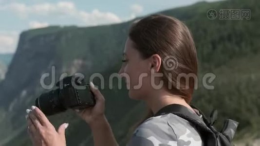 女旅行者站在山顶时，用相机拍摄美丽的照片。 特写视频