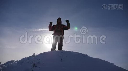 旅行者在白雪皑皑的山顶上为他的胜利而欢欣鼓舞，跳跃和挥动他的手臂，一个快乐的人。 快乐的游客视频