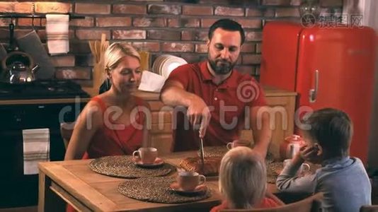 一个幸福的家庭在一个舒适的夜晚坐在厨房的桌子旁，旁，着妈妈烤的蛋糕吃晚饭视频