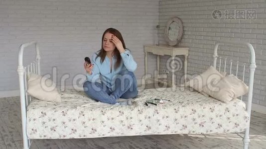 一个悲伤的女人坐在床上，手里拿着血糖仪。 高血糖。视频