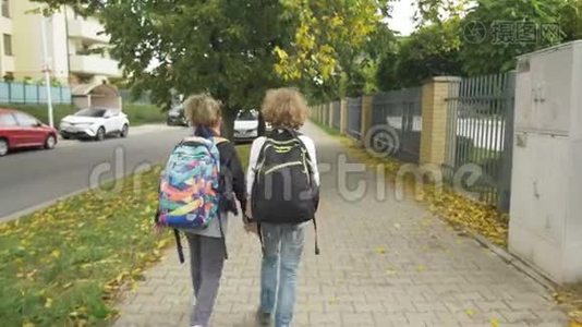 两个背包的朋友将在城市街道上的汽车上上学。 妹妹和她的哥哥回学校。 太阳是视频