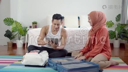 年轻的穆斯林夫妇准备旅行支票和旅行箱视频