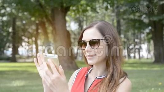 一个年轻女孩在一个夏天公园的视频通话视频