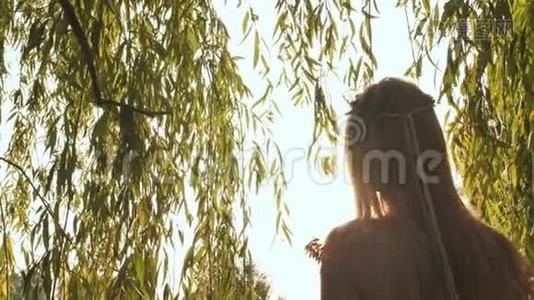 女孩在阳光下传播柳枝。视频