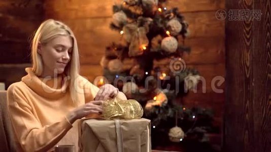 金发女人把圣诞礼物包装成纸。 快乐的女人打开圣诞礼物。 设计礼品盒手工制作。 交货视频