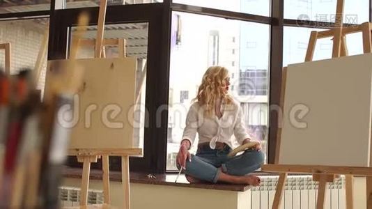 性感的女孩坐在窗台上，画室里有画笔和画架视频