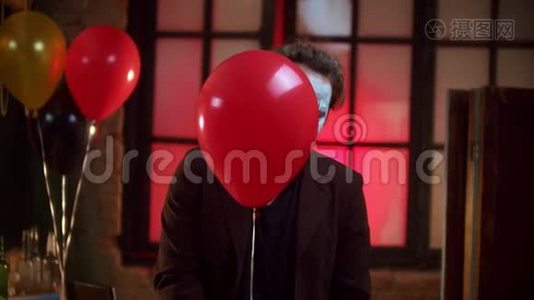 一个可怕的小丑从红色气球里微微偷看，露出令人毛骨悚然的微笑视频