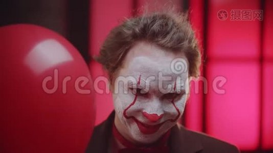 一个可怕的小丑从红色的气球里偷看，回去的时候令人毛骨悚然的微笑视频