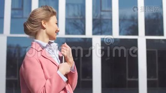年轻的商务女性在办公楼背景上使用平板电脑视频