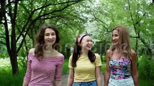 三个美丽的多民族女孩朋友一起笑着走公园。视频