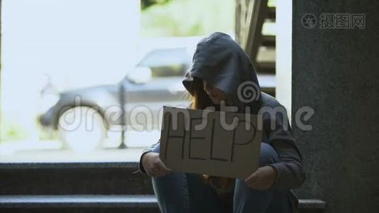 穿着连帽衫的伤心少女在街上举着帮助标志，男人伸出援手视频