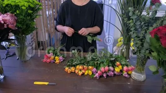 花商在花店里用五颜六色的玫瑰，双手特写，创造出一大束。视频