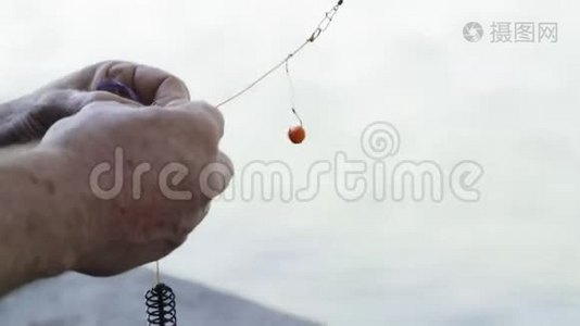 特写镜头，一个老渔夫的手在钓鱼钩上踩着鱼饵视频