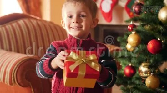 快乐微笑的小男孩在盒子里拿着圣诞礼物的视频，并在镜头中展示他的礼物。 接收儿童视频