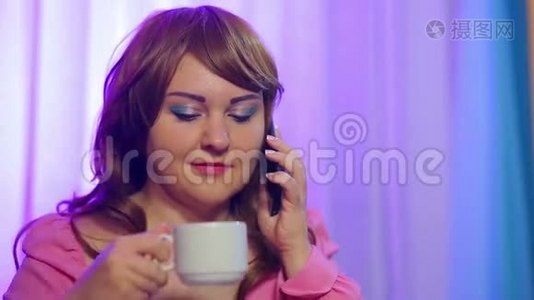 红发女人在咖啡馆的一张桌子上喝着咖啡，打着电话视频