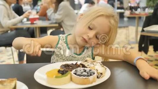 女孩在一个模糊的背景下在咖啡馆里吃各种蛋糕。视频