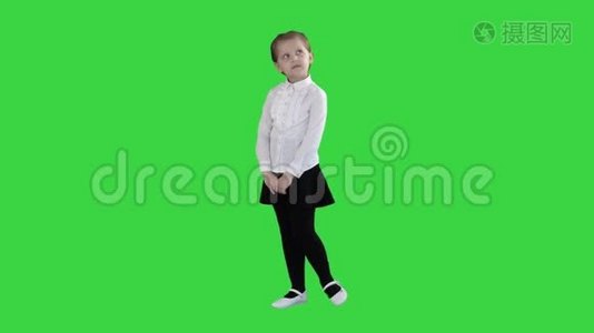 可爱的学龄前女孩站在害羞的周围，在绿色屏幕上思考，Chroma键。视频