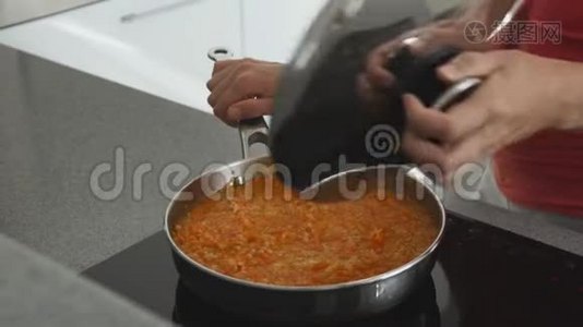 厨房里的女人在炉子上准备着一个煎锅，里面有扁豆和胡萝卜。 健康的饮食有很多视频