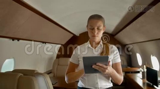 女商人在空中私人飞机上用数字垫上网视频