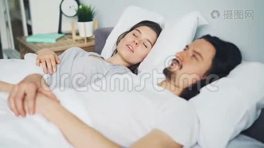 不快乐的男人丈夫用枕头遮住头，妻子在床上打鼾视频