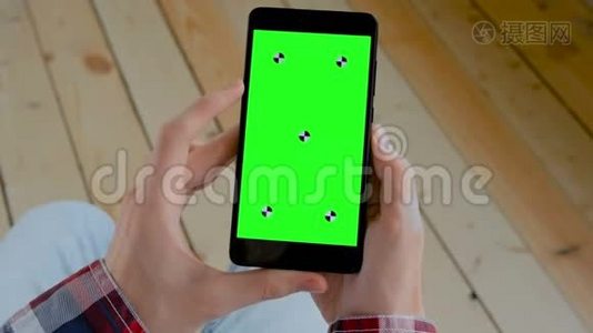 男子手持黑色智能手机与空白绿色屏幕-色度关键概念视频