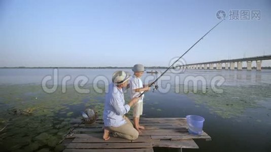 快乐的一家人钓鱼，快乐的父亲和快乐的小儿子一起在水边的码头钓鱼视频