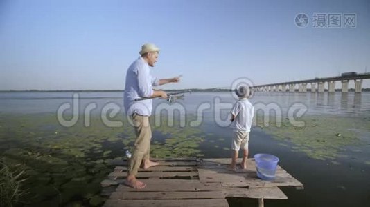 逗乐的父亲和儿子fishermÐ°欢快的，欢快的小男孩戴着草帽在码头的码头上钓鱼视频