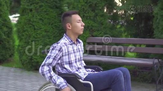 残疾的亚洲青年男子乘坐轮椅在公园慢莫视频