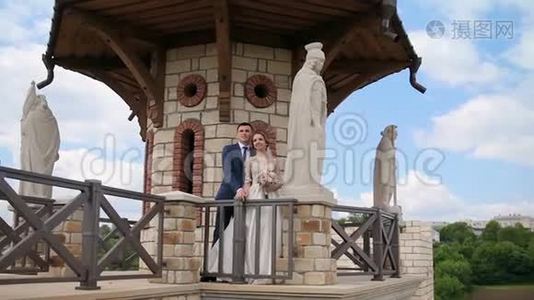 新婚夫妇走过一座古老的石堡，里面有宏伟的石像。视频
