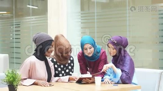 穆斯林亚洲和非洲妇女头巾和头巾使用笔记本电脑在咖啡馆视频