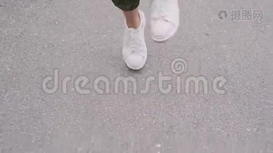 穿着白色运动鞋的时髦女孩正在公园里跳跃，用便携式扬声器听音乐。 特写视频
