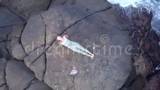 苗条的女人站在海边巨大的灰色石头上做瑜伽姿势视频