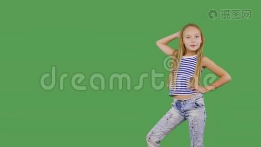 年轻女孩模特在绿色背景上摆着前摄像头。 少女微笑着，看着镜头拍照视频