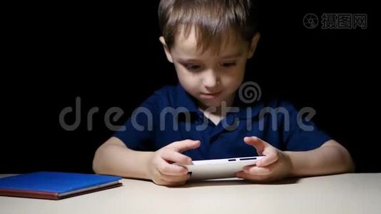 一个快乐的孩子在晚上用智能手机快乐地看着一幅漫画，微笑着视频