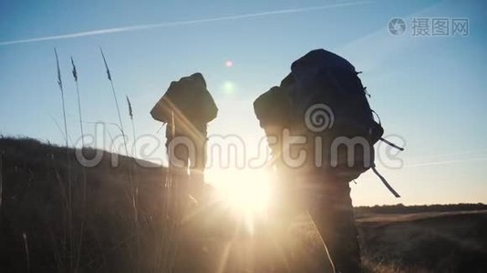 两名游客团队合作，背包慢动作行走，在夕阳的阳光下走着剪影。 两个视频