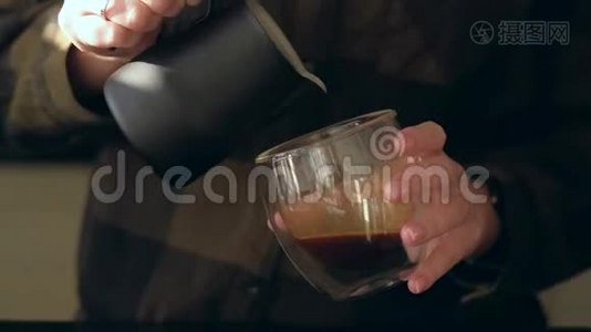把咖啡师的手收起来，在咖啡杯里倒入温牛奶，用于制作拿铁艺术。视频