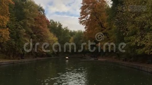 秋天的公园里有五颜六色的叶子和公园里的一个池塘。 秋天池塘的全景。视频