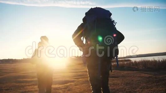 两名游客一起背着背包，慢动作行走，在阳光下剪影，生活方式，阳光照耀。视频
