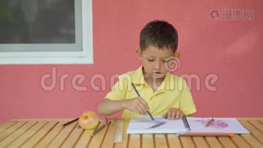 可爱的小男孩在木桌上的相册里画画视频