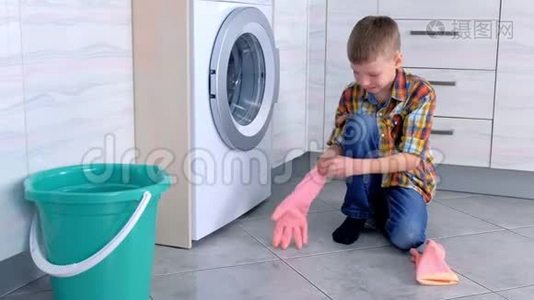 男孩戴上橡胶手套清洁厨房地板。 儿童`的家庭责任。视频