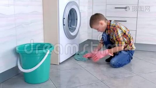 穿橡胶手套的男孩在厨房里洗地板。 儿童`的家庭责任。视频