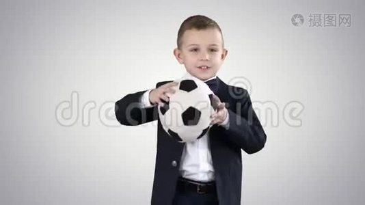 穿正式西装的男孩在梯度背景下踢足球。视频