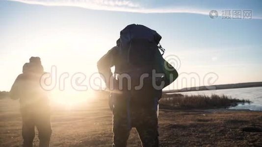 两名游客一起背着背包，慢动作行走，在阳光下剪影，阳光照耀着生活方式视频